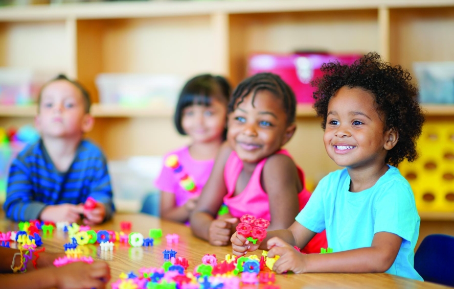 Happy KALE preschoolers playing together at a classroom table